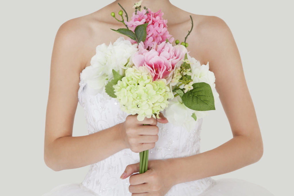 Midsection of young bride holding fresh bouquet